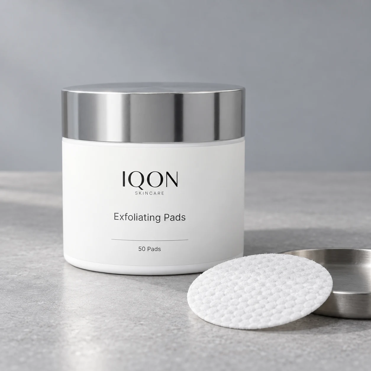 IQON Exfoliating Pads with one treatment pad on a silver dish